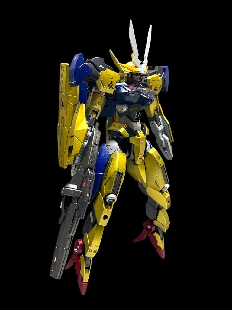 【機体解説】XGF-04ガンデリクサーは、宇宙議会連合の量産型無人MSである。MS型ガンビットであったガンヴォルヴァやガンドノードの系譜を継ぐ機体であり、開発・製造は議会連合の特務機関として存続していたオックスアース社が担っている。 パイロットは、エリクト・サマヤの遺伝子情報から生成された拡張意識AIエリィⅩⅣである。彼女はスレッタ・マーキュリーらに続く14番目のリプリチャイルドであるが、産まれた時からその肉体を持つことは無く、データストーム空間で生きており、自らこそ肉体というくびきから解き放たれ最初に永遠を手にした生命体を自負している。 機体名はGUNDと不老不死の妙薬“エリクシル”にかけられており、エリクシルがかつて錬金術により精製されていた事から、その装甲は黄金色の輝きを放っている。