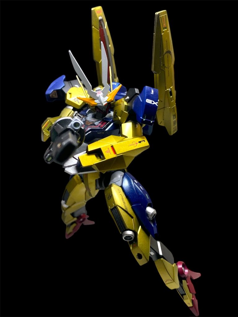 同じ頃、囚われたスレッタと漆黒の騎士の前に、とある人物が姿を現した。 「ど、どうゆう事ですか、コレ!?やっぱり、ザザ商会と宇宙議会連合ってグルだったんですか?イエル・オルグさん…いえ、サビーナ先輩!」 2人の牢の前には、イエル・オルグ仮面を外した、かつてのグラスレー寮生、サビーナ・ファルディンが立っていた。 「そうではない。我々はあくまで、取引関係にあるだけだ…私には、その男が再び戻って来てくれれば、それだけでよかった…」 「漆黒の騎士さん?ふ、二人は、やっぱり、お知り合いなんですか?」 「彼の中に今あるのは、シャディク…シャディク・ゼネリだった男の人格だ。一か月前、私はシャディクが収監されていた第七監獄を襲って連れ去った。彼自身がそんな事を望んでいないのはわかっていたし、そんな事をしたところで自分達に未来が無い事もわかっていた…それでも、、、それでも、死刑を目前にして、罪を全て受け入れた奴を一人でいかせる事など出来なかったんだ… そんなの女の情念だろうと揶揄されもするだろう。あいつがイエル・オルグと呼ばれていた時代からの長い付き合いだ、友としての情もある。ただ、恋愛感情とか、友情とか、そうゆう名前の付けられた思いでは括りきれない気持ちが、私にそうさせたのだ。 連れ去ったその後は、私の手で楽にしてやるつもりだった。肉体が科せられた刑罰を受けたとしても、せめてその精神だけは救ってやれないかと思い、私は使われずに保管されていた古いGUND義体を用意した。作り物の身体に、魂だけを移しかえる…まるで、転生の儀式を行う魔女のようだったよ。 データストーム空間を介して、意識のみを移しかえる事には成功したかにみえた。だが…目覚めた彼の意識は混乱し過去の記憶の殆どを失っていた。原因を探したところ、それがGUND義体内に先に書き込まれていたデータである事が分かった。そして、そのデータのロックを解除する事が、彼の意識の混乱を取り除く為の唯一の方法だと分かったのだが、目を離した隙に彼は私の前から失踪してしまい、組織の力を利用してあらゆる手を尽くしてその行方を探していた。 宇宙議会連合と手を組んで仮面武闘会を開いたのは、シャディクを見つけ出すという利害が一致したからに過ぎない…」