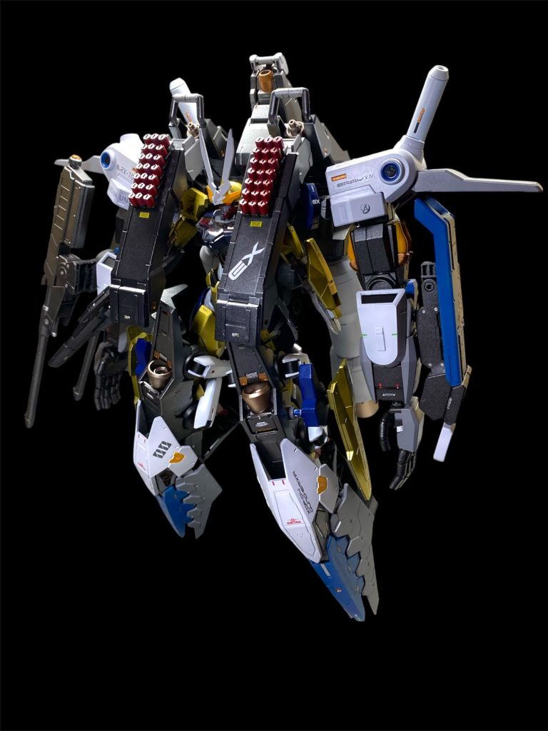 また、ガンドノードと同様に大型MAオプションMRX-103Zアルカナユニットが用意されており、合体する事で、火力、防御力、推力、航続距離などのあらゆるスペックが大幅に増強される。ウミガメのようなフォルムだったガンドノードのそれとは異なり、巡航形態から人型に展開して、文字通りガンデリクサーの四肢を拡張する事で戦闘力を向上させる。ビーム砲を内蔵した巨大な腕部などからはかつて“虎の手”などと呼ばれた大型GUND兵器の影響が見て取れる。各部は本体から分離して大型ビットとして全方位攻撃が可能な上に、ルブリス量産試作モデルなどに装備された自爆型ガンビット“キローニアン”42機も搭載する。