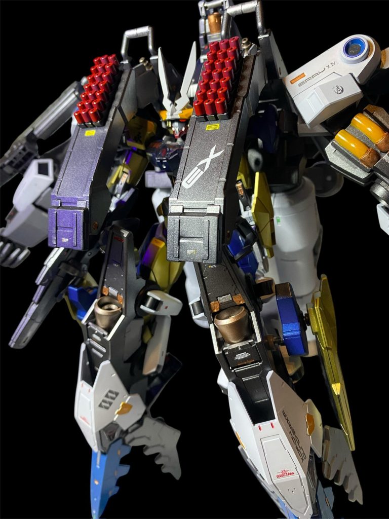 「偽善ヲ装ッタ、綺麗ナ言葉ダケニ惑ワサレルナ!」そこへ、漆黒の騎士のミカエリス・ノームも割って入る。「我ガ義体ノ中ニ僅カニ残サレテイタ記憶ガ語リカケテイル。エルノラ・サマヤハ、データストームニ侵サレタ身体ヲ抱エナガラモ、家族達ト共ニ過ゴス限ラレタ時間ヲ大切ニシテイタ。永遠ナド望ンデハイナカッタハズダ!」 「エリィⅩⅣ、アルカナユニットの準備を。」議長のその言葉と共に、無数のMAらしきユニットが射出されると、それは次々とガンデリクサーとドッキングを始めた。 「聞き分けの無い方たちも、従順なる方たちも、皆平等に、生まれ変わるのです。」