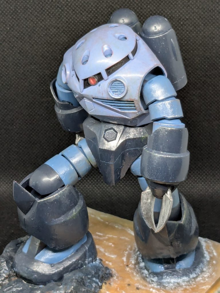 やや上からです。モノアイが出張ってる表現を実験的に行いました。これだけで出っ張っているとどう動くのかと思ってしまいます。多分やりすぎです。ウェザリングの赤錆が本体色の青と対比されすぎ感があります。もう少し黒を追加すると自然になるかもしれないです。