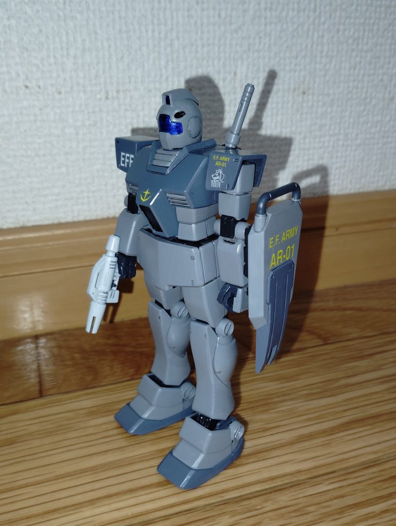 　正面素立ちです。　前回も紹介しましたが、基本塗装はニュートラルグレーとミディアムブルー、関節などがミッドナイトブルーです。　バイザーや額のメインカメラなどは表をクリアーブルーで塗装し、裏から銀色を塗ってあります。　ちなみに塗装やマーキングは、ドリームキャストのゲームソフトである本家「機動戦士ガンダム外伝　コロニーの落ちた地で・・・」ではなく、かつてゲームセンターで大好評だった「戦場の絆」というアーケードゲームに登場するパターンを参考にしました。　そのため、実は当初は同時製作していたジムキャノンと統一感を出すためにも、バイザーは一般発売のジムと同じクリアーグリーンっぽいパーツを使用する予定でした（「戦場の絆」では、一般機のジムと同じような緑がかった色のバイザーだったので）。　しかしながら、手持ちの一般発売のジムのバイザーがひとつしかなく、自作であの絶妙な青緑色を再現するのは無理だと判断したため、今回はクリアーブルーで塗装することにしました。　こんなことなら、２、３年前に製作したリアルタイプカラーのジムのバイザーにこの「ジム（ホワイト・ディンゴ隊仕様）」のパーツを使い、一般発売のクリアパーツは取っておくんでした・・・。