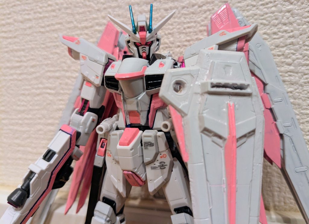 コラボ画像にあったシールド構えての1枚。白ピンクのフリーダムも可愛いカッコいい感じですごく良いです!顔は隈取りとくちばし、アンテナ中央を蛍光ピンク、カメラアイとメインカメラはメタリックピンクにしました。おかげで目が光っている感を出せたかと思います。アンテナは緑っぽい青という感じだったので、水性のエメラルドグリーンの上からマーカーのガンダムメタブルーを塗り、それっぽく仕上げました。シールドも全面ガンダムホワイトで塗装し、赤だった部分を蛍光ピンクにしました。