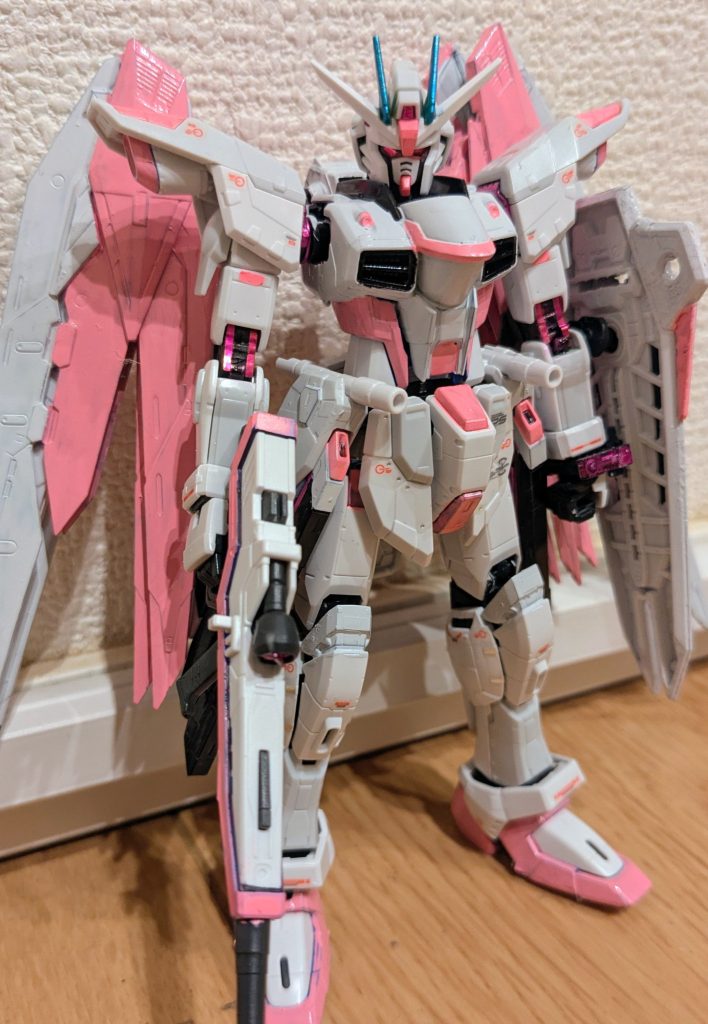 トップ画像とはサイドを変えて1枚。ピンクだけで3種類使用しました。羽、スリッパあたりは水性塗料のピンク。赤だった部分など細かいところは、ガンダムマーカーの蛍光ピンク。肩や肘、膝関節はガンダムマーカーのメタリックピンクです。あとは胴体、シールドの黒い部分はガンダムホワイトで塗装してあります。