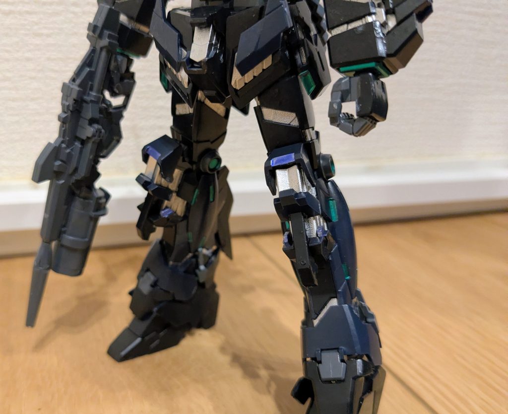 下半身をアップで1枚。脚はなおさら、塗り分けが色々見える部分かと思います。膝頭の上下展開部分、腿両側、足首ガードの上部が成形色。それ以外の黒はティターンズブルー1です。脚もアポジモーター部分はメタリックグリーン。で、脚の部分部分に紫になっているポイントがあるな〜て思ったので、そこをマーカーのメタリックバイオレットで塗装しました。そして、完成し、写真とってから気付いたんですが、よくよく見ると…スリッパ部分内部のサイコフレーム、紫っぽいんですよ…。そこだけ塗り直しても良かったかな〜とも思ったんですが、解体するのも面倒なのでそのままにしてあります(笑)