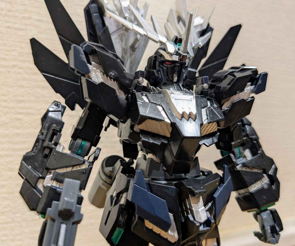 バストアップで1枚。塗装に使用したのは4色。写真だと見分けがつきにくいですが、サイコフレーム部分はマーカーのシャインシルバー。首元やアンテナ、背中のたてがみ部分はマーカーのシルバーで塗装。色の当たり具合からどっちもシルバーなんだろうけど、サイコフレーム部分は鮮やかなシルバーでそれ以外はくすんだシルバーな感じに見えたので、塗り分けてみました。同じく、本体色も真っ黒に見えるんですが、肩の先端の回転部分や腰の展開部分はグレーっぽいような本体と違う黒な感じだったんですよね。ただ家にグレー系が何もなかったので、本体色をティターンズブルー1、違った感じの黒部分を成形色のままで分けてみました。シルバーも黒も、アップにしても分かるような分からないような微妙な違いですが(笑)あとはフレームの隙間や関節の丸部分、アポジモーター部分をマーカーのメタリックグリーンです。