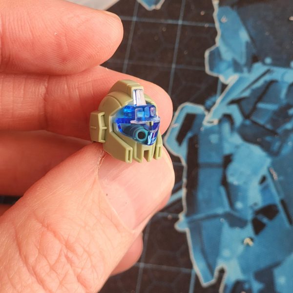 塗装前の細部をもう一度見てみましょう。バイザーから見えるピンが気に入らなかったので、少し隠すことにしました。最初は塗装で隠そうと思ったのですが、たまたま高級クッキーの光沢のあるパッケージを見つけました。薄いプラスチックシートのようなものです。ラッキーでした！マスキングテープを使ってバイザーの形を作り、切り抜いた後、銀色のプラスチックを頭部に押し込みました。仕上がりは格段に良くなりましたよね？それから、バイザーの小さな接続部品をうっかり折ってしまいました。テストのためにピンセットでバイザーを外そうと力を入れたのですが、滑ってしまい、部品が部屋を横切ってどこかへ飛んでいってしまいました。ああ、大変だ！塗装後に接着剤で直さなければ。脚の裏側と後翼の継ぎ目も少し消してみました。翼のパネルラインが少し乱れていたので、きちんと彫り直しました。添付の写真は、脚部の彫り直し前後の比較です。最後に、細部にさりげないディテールを加えるため、装甲の各所に穴を開けました。-Here is an extra look at some details before painting.I'm not happy with the visible peg through the visor. I've decided to try and hide it a little.At first I thought about doing this with paint but then I happened across some shiny packaging from some luxury cookies. It's like a thin sheet of plastic. How lucky is that?&nbsp;I used masking tape to try and achieve the shape of the visor. Once cut out, I squeeze the silver plastice into the head.The result is so much more satisfying, don't you think?I also actidentally snapped a small connection piece from the visor.I had to apply some force with tweezers to get the visor off after testing, they slipped and the damage was done. The piece went flying across the room, into the abyss. Oh man! I'll have to glue it after painting.I've also tried some more seem removal on the backs of legs and on the back wing. I made sure to rescribe the panel line on the wing as it got a bit messy. The photo attached here shows a before and after of the legs.Finally, to add subtle detail I decided to drill some holes on various parts of the armour.&nbsp;（2枚目）