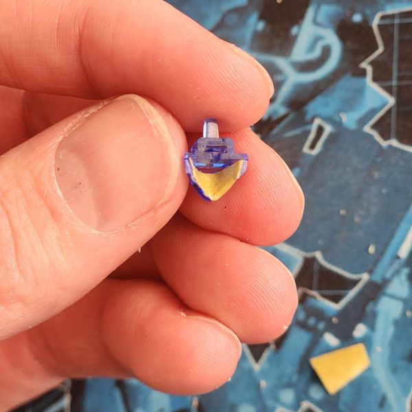 塗装前の細部をもう一度見てみましょう。バイザーから見えるピンが気に入らなかったので、少し隠すことにしました。最初は塗装で隠そうと思ったのですが、たまたま高級クッキーの光沢のあるパッケージを見つけました。薄いプラスチックシートのようなものです。ラッキーでした！マスキングテープを使ってバイザーの形を作り、切り抜いた後、銀色のプラスチックを頭部に押し込みました。仕上がりは格段に良くなりましたよね？それから、バイザーの小さな接続部品をうっかり折ってしまいました。テストのためにピンセットでバイザーを外そうと力を入れたのですが、滑ってしまい、部品が部屋を横切ってどこかへ飛んでいってしまいました。ああ、大変だ！塗装後に接着剤で直さなければ。脚の裏側と後翼の継ぎ目も少し消してみました。翼のパネルラインが少し乱れていたので、きちんと彫り直しました。添付の写真は、脚部の彫り直し前後の比較です。最後に、細部にさりげないディテールを加えるため、装甲の各所に穴を開けました。-Here is an extra look at some details before painting.I'm not happy with the visible peg through the visor. I've decided to try and hide it a little.At first I thought about doing this with paint but then I happened across some shiny packaging from some luxury cookies. It's like a thin sheet of plastic. How lucky is that?&nbsp;I used masking tape to try and achieve the shape of the visor. Once cut out, I squeeze the silver plastice into the head.The result is so much more satisfying, don't you think?I also actidentally snapped a small connection piece from the visor.I had to apply some force with tweezers to get the visor off after testing, they slipped and the damage was done. The piece went flying across the room, into the abyss. Oh man! I'll have to glue it after painting.I've also tried some more seem removal on the backs of legs and on the back wing. I made sure to rescribe the panel line on the wing as it got a bit messy. The photo attached here shows a before and after of the legs.Finally, to add subtle detail I decided to drill some holes on various parts of the armour.&nbsp;（3枚目）