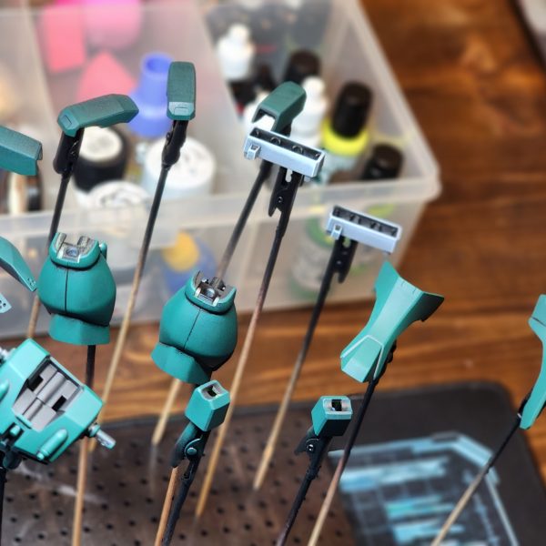 パーツの塗装がかなり進んだので、期末試験前に最後の進捗状況をお伝えします。自分で色を調合することにしたのですが、当初のカラーモックアップから少しずれてしまいました。全体的に、本来の色よりも青みがかったターコイズブルーになってしまいました。うっかり…まあ、これは「カラーガイド」と呼ぶしかないでしょう。仕上がりに満足できなかったため、多くのパーツを何度も塗り直しました。私は自分の作品に見栄えの良さを求めているんです。例えば、胴体部分は思い通りの仕上がりにならず、3回も塗り直しました。これが今の私のベストだと判断しました。小さな鮮やかな緑色のパーツは、あまりにも小さかったので、ほとんど省略しようかと思ったのですが、結局塗ってよかったと思っています。全体の印象を良くしてくれるといいのですが。実は、新しい作業用ランプを自分へのご褒美に買いました。あれがなければ、細かい筆塗りのパーツは到底無理だったでしょう。ゲームのレベルが上がって嬉しいです。ゲームといえば…青と緑の組み合わせはモンスターハンターのブラキディオスを思い出させますね。いつかこんな風に全身をカラーリングしてみたいです。-I've managed to get a lot of the parts painted up and thought I'd share one final update before finals.I decided to mix my own colours and drifted away from my original colour mock-up. The whole build is looking a little more blue/turquoise than it should. Oops... I suppose we could just call it a 'colour guide'.Alot of the parts I had to re-paint numerous times because I wasn't impressed with the results. I want my models to look impressive. The torso for insatance was re-painted 3 times because I could not achieve the look I wanted. I've decided this was the best I could do.I very nearly skipped out the small bright green parts because they were so tiny, but now I'm glad I didn't. I hope they add to the overall impact of the build .I actually treated myself to a new work lamp, a lot of the tiny brush parts would not have been possile without it. I'm happy I leveled up my game.Speaking of games... The blue and green together remind me of Brachydios from Monster hunter. Would love to do a full colour scheme like this one day.&nbsp;（4枚目）