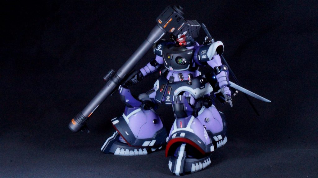 【斜め前】使用した塗料はGSIクレオスのガンダムカラーを多く使いました。配色はかなり悩んだんですが、AI生成が元の紫ベースだったので、自作も同じ方向性にしようとガラッと変えることはしませんでした。メインのパープルはMSパープル、紺色部分は最近出たνダークブルー、膝などの濃い紫はHi-νパープル、胸部のグレーはMSグレージオン系、赤はハーマンレッド、白はクールホワイトになります。また、今回初めてガイア プリズムブルーブラックを使ってみました。(gundam-kao2)次に作る機体用に買ったのですが、こちらで先に使ってみました。腰のブースターと肘の関節部に使っています。光沢と艶消し両方の仕上げを混ぜてみました。わかるでしょうか？(zaku-kao4)