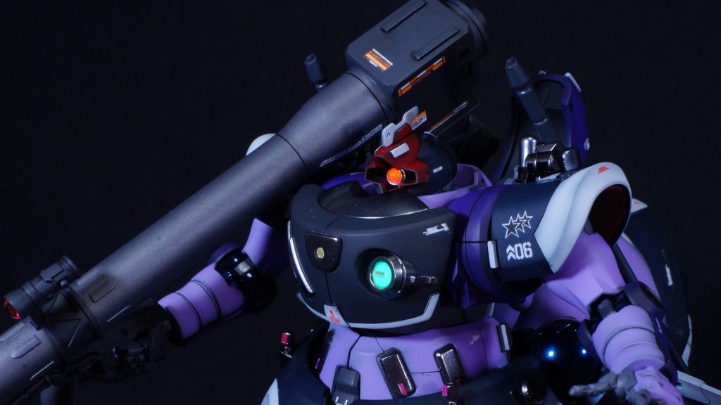 今回もいつものように全体的なスジボリの追加やプラバンなどによるディテールアップを施しています。頭部はひさしを前方に伸ばし、角？のような飾りを追加しています。機体番号06でオルテガ機として作成しましたので、エース機なら頭部に角的なものがついていていいのでは？という思い付きです。(zaku-kao4)モノアイはハイキューパーツのルミドームとベース部にSPプレートを使っています。胸部のフラッシュライト的な？緑色の部分ともどもUVライトで光ります。(zaku-kao5)