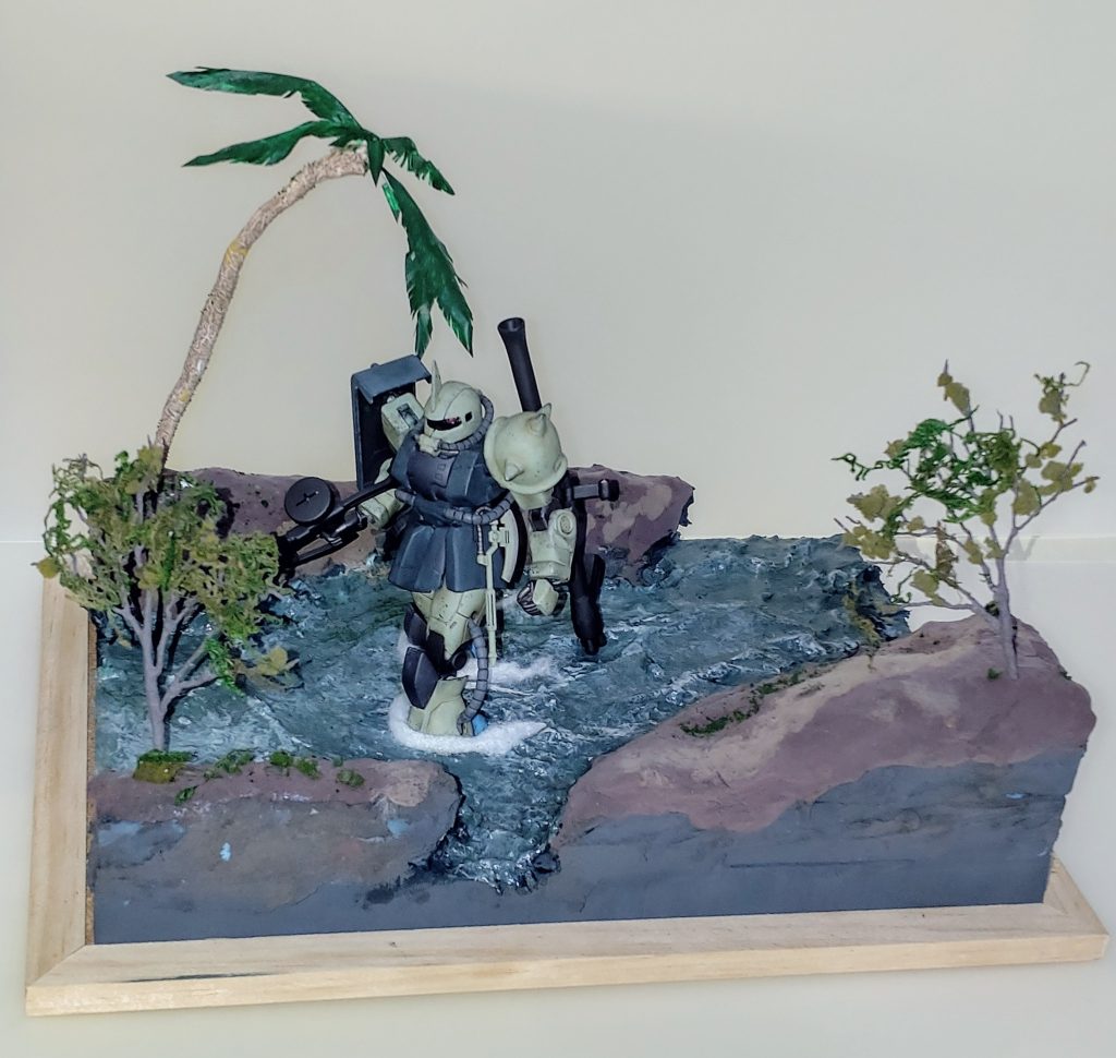 08小隊と言えば地上での運用シーンが印象的です。ということで密林内の川での移動をイメージしてベースを製作してみました。100均で購入した素材が主なベースですが、二本の木はトミーテック製の物にスポンジ等を加えてみました。ヤシの木は今回初めて針金ベースでマスキングテープを巻いたものを自作してみましたが、少しばかり物足りないと思えたので今後のベース製作の課題になりました。