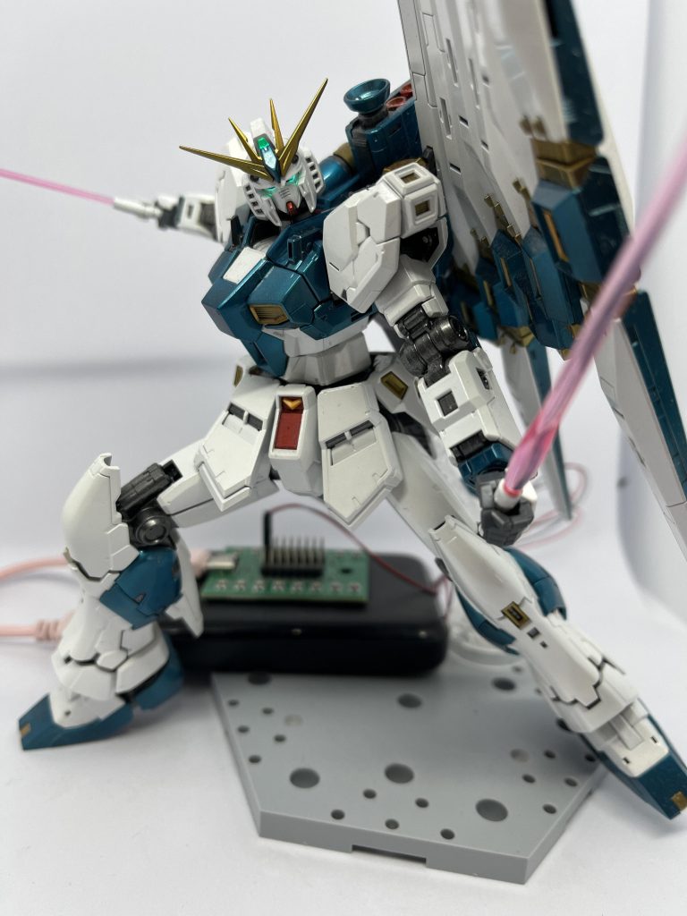 ビームサーベル二刀流でポーズを決めたアピールショットです。躍動感と攻撃的な印象が出るよう、振り抜く直前のような構えを意識しています。左右に広がるシルエットにより、機体のプロポーションや可動域の広さが分かりやすいカットになっています。全塗装による質感やエッジの立ち方も、このポーズでしっかり伝わるようにしました。カメラアイの発光も相まって、シンプルながら迫力のある一枚に仕上がっています。