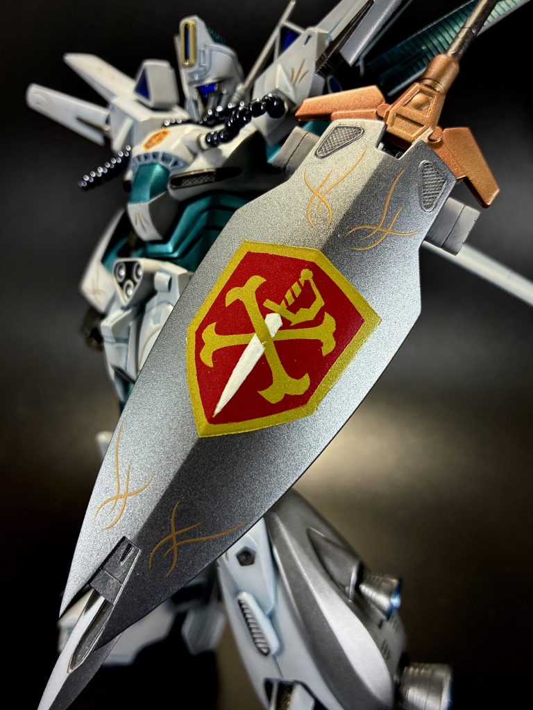 シールドに剣を収納するというのをやりたくて、元のシールド表はそのままに裏面に剣をさす鞘を自作しました。一番困ったのがシールドのクロスボーンバンガードマーク。ジャンクなのでデカールなんぞ付いていません。デカール自作する環境もないので、覚悟を決めてマスキングの繰り返しで塗装表現しました。