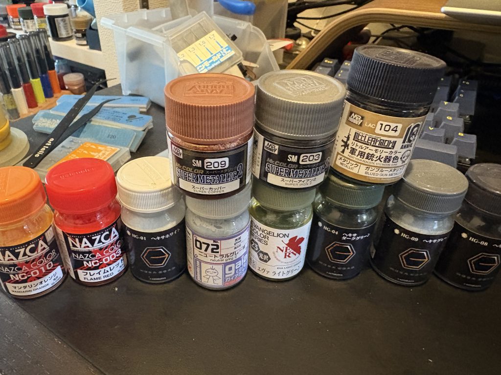 下地はシルバーサフを使用。写真の塗料を使いましたが、迷彩で使用した白はニュートラルグレー1に変更しています。写真ではグレーに見えますが、肩のパイプやバーニアはテラクロームを使用。肩はマスキングゾルを使ったせいか触り過ぎたのか、くすんでしまいました…ワンポイントにシュナイダーのメッキ調ペンを使用。レッドチップ代わりにバンダイ3Dメタリックシールを使用。これ地味にブラックライトで光ります!つま先など墨入れはシタデルカラーベースホワイトにAQUOSの蛍光レッドで墨入れ。