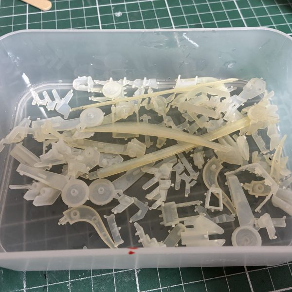 はじめてのメッキ剥がし【用意したもの】・クレオスうすめ液・蓋つき瓶 100円×2・ドリッパーのフィルター・キッチンハイター(塩素系)調べても工程を些細に記載したものがなかなか見つからないのでまとめました以下、工程【写真2〜4枚目】・ゴールド部分を剥がす作業・メッキではなくクリアイエローを剥がす作業なので、ランナーから落としたパーツを瓶に入れてシンナー風呂・漬けた瞬間から液剤は黄土色に染まるぐらいにはスピーディーに色が抜けていく・蓋つき瓶にした事で寝かして振ったりが可能だったのでムラなく色を落とすことが出来た・5分もかからずゴールドは無くなる・濾過作業は5回ほどに分けて少しずつ。紙フィルターは片付けも含めて慎重になる必要がなく正解でした【写真5〜7枚目】・本題のメッキ剥がし・ハイターにも色々と○○系というような種類があるようで、実例で見かけるキッチンハイター(塩素系)を用意した・長物は平らなトレーに…しましたがゴールドと同じく瓶に突っ込んで振った方が早かった・漬けて2分ほどで小さいパーツはメッキが溶けて下地の乳白色に・瓶を寝かして転がしたりでこちらも5分とかからず全てのパーツが下地の乳白色に・失敗したなと思ったのはハイターは泡立つので振りすぎ注意。泡で取り出しにくくなる上に今回のように乳白色のパーツは取り忘れがないか見分けにくい。正しく「漬ける」でいいと思った 【やってみての感想】・想像以上に時間がかからない。洗う時間のほうが長い・突貫なら総作業を30分ぐらいでやれそう・メッキごとに特長もあるようなので、今回はガンプラメッキの場合の結果でおさめようと思う【良かった点】・濾過用にフィルターともう一つ瓶を用意したこと・蓋つきの瓶【反省点、困った点】・ハイターを泡立たせた・プラモだけの用事にしてはハイターのボトルがデカい・洗い物が多い以上です。何かの参考になれば(7枚目)