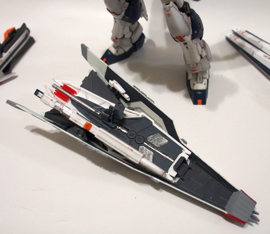 腰部のバーニアは、もともとビームライフルの懸架用に空いていた穴を利用して装備しています。行き場の無くなったビームライフルとビームサーべルは、シールド裏にプラバンでウェポンラックを作成し、ここに吊るせるようにしました。