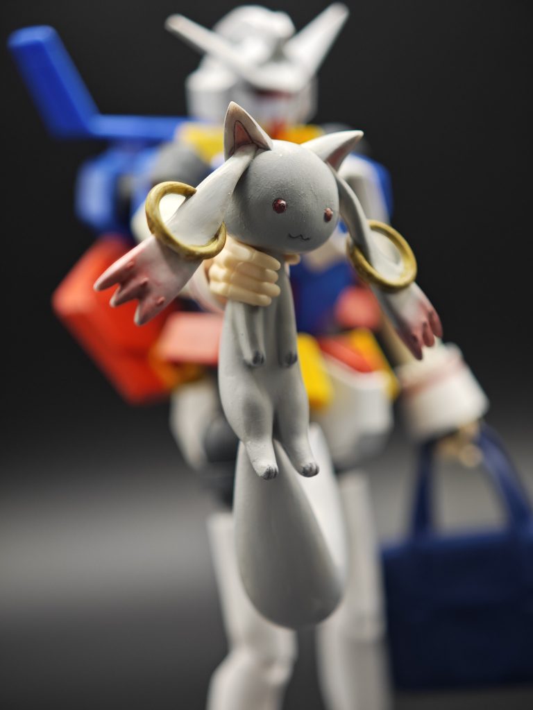 …まぁ言いたい事はわかりますよ、完全に不純物がひとつありますよね。それがコイツ…謎の生物の死骸です…。実は私も見た目から魔法少女ものでお馴染みのマスコット説やマスコットに見せかけて実は黒幕的なヤベェ奴説 …とかもの考察もしてみたのですがそれなら素直に4足なり2足で立っている形で立体化されると思うのでこの脚をだらんと垂らした脱力ポーズなのが不自然、そしてとてもペットやマスコットを扱うとは思えない首根っこ掴む持ち方の持ち手が付属している事がすごく違和感だったんですよね…。そして決定的だったのが実はこのキット、今回は作らなかったのですが謎の卵的な物体も付属してるんですよね…よって導き出された答え、それはスバリ、この謎の生物の正体は家畜を襲う外来生物です。現実世界でもアライグマやらハリネズミやら見た目は可愛くても被害をもたらす外来種が問題になっておりますし、一見マスコットに見えても実は危険な動物であるという事は十分に考えられます。害獣は農家の天敵…その事実を踏まえると一見すると不自然な「動物の死骸を持った女学生」という構図も家業の農業を手伝う心優しい女の子が畑や家畜を襲う害獣の駆除を行ったと考える事が出来るので駆除した害獣の死骸がキットに付属しているという謎にも納得がいくというものです。そんな考察を踏まえて私が導き出した「魔法少女まどか☆マギカ」あらすじはこうです…ちょっと地方にすむ中学生(高校生?)のまどかちゃんの朝の日課はおばあちゃんの家の農業を手伝う事…そして家畜のニワトリの卵や作物を食い荒らす害獣の駆除も農家のお仕事。現実とちょっと違うのがこの害獣が魔法で生み出された魔法生物だという事…まどかちゃんや仲間達はおばあちゃんの畑を守るために魔法少女として戦うのです。…たぶんこんな感じの日常スローライフ系魔法少女みたいなのが大まかなストーリーだと思われます。朝の日課で害獣駆除に勤しむまどかちゃん、その日は処理に少し手間取ってしまい遅刻しそうに!「いっけな〜い、血抜きに手間取っちゃった☆」とか言いながら謎生物の死骸を片手に駆けてくちょっとドジなまどかちゃんが曲がり角で都会から引っ越してきたイケメン転校生(CVゼクス・マーキス)とゴッツンコ…みたいな場面が容易に想像出来ますね。CVとかは妄想ですがきっと当たらずも遠からずって所でしょう、きっと2026年公開予定の劇場版は昨今の情勢に合わせて駆除反対をかかげ自治体に苦情電話をかけてくる保護活動家との激戦が描かれるものと思われます…人類の敵は人類であるという深いテーマです…。