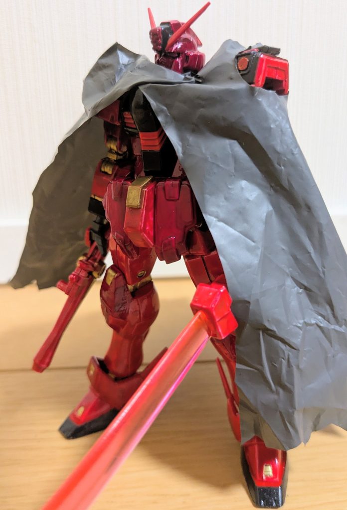 逆サイドから全身像を１枚。色レシピは次の通り。赤部分:メタリックレッド（赤基本）黒部分:ティターンズブルー１（黒全部）マゼンタ部分:メタリックレッドの上から色ノ源マゼンタ（頭部、上腕、腰回り、スカート、膝、クリップ部分）ゴールド部分:ガンダムゴールド（マーカー塗装）&nbsp;今回悩んだのはマゼンタ部分ですね。マリン船長コラボ機のピンクっぽいような赤っぽいようなマゼンタ部分。それっぽい色ないかな〜と量販店の塗料コーナーを眺めていると、目に着いたのが３割引で売っていた色ノ源マゼンタ！ただ、色味添加剤ということで、そのまま塗ってもぼんやりするというか微妙な感じになるので、メタリックレッドの上からやったら結構予想通りの良い感じになりまして、満足満足！頭部は上記のマゼンタに、アンテナとくちばしはメタリックレッド。カメラアイは悩んだ上で、船長のオッドアイをイメージして、右をガンダムゴールド、左をメタリックピンクでマーカー塗装です。メタリックピンクは影のあるところで光に当てると赤っぽいキラキラに見えるから良いかな〜と思って採用。顔のキズは、マゼンタ塗装が乾いてから削り出すことで、CGイラストのようなピンク線を出すことができました！