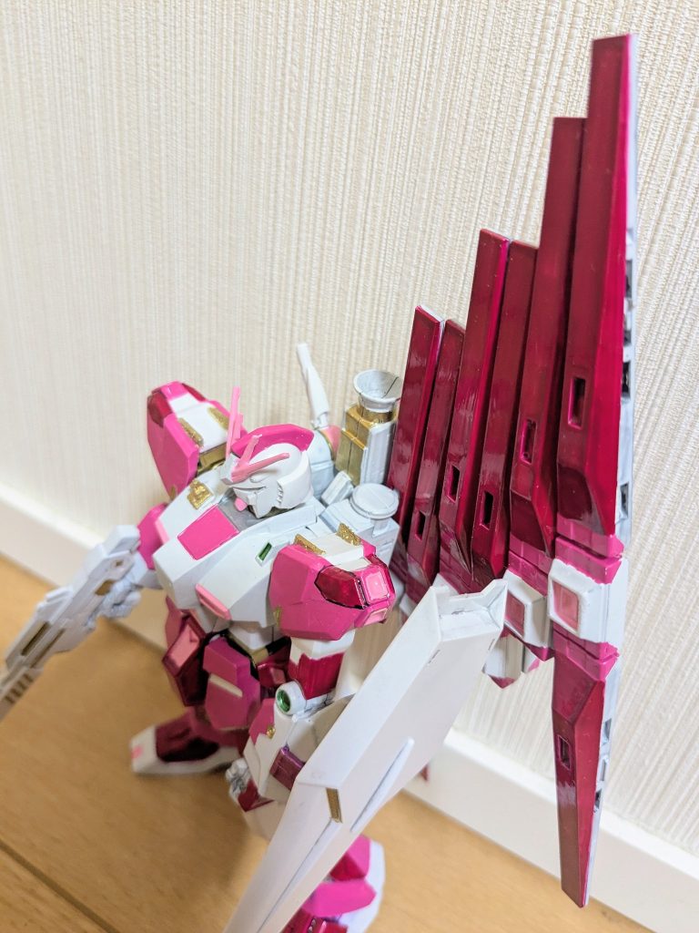上から１枚。これ見ると分かるんですが、公式CG見てだいぶ色味寄せたつもりです。肩の金の突起や右胸上部のアンテナっぽいものは、ランナータグを使った簡単工作です。脚の関節はメタリックピンク、腰内部と肩関節はゴールド、肘関節と手は白と、ホント色々塗り分けしました！その分、見た目鮮やかですごく好きな色合いの機体になりました。フィン・ファンネルも良い味出してます。シールドが超シンプルなのも、一応公式準拠。