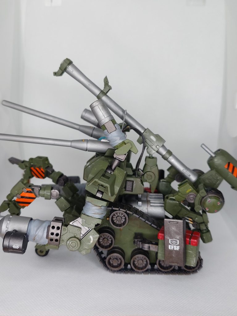 キャタピラを上下逆さまにして車輪の位置を変えています。腕はほぼ30MMのパーツです。前後に補助脚（車輪付き）があります。前側補助脚には障害物を排除できるようなアームが付いてます。両肩はビーム砲の想定でパイプを接続。背中のバズーカらしき奴はカートリッジに謎装置が付いており、実体弾かエネルギー弾かは不明です。（笑）&nbsp;