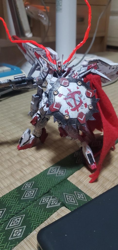 シールドの赤いマークはドゥームスレイヤーのヘルメットに刻まれたマークを筆塗りで仕上げました。目の赤い光エフェクトはビルダーズパーツのビームエフェクトを折り曲げ、中に小型磁石を埋め込み、蛍光塗料で塗装したものです。マントはフェルトを切り、磁石を埋め込んだものです。