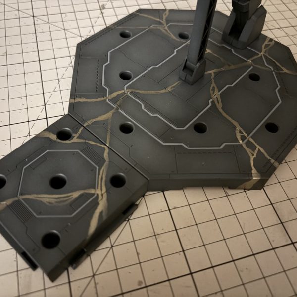 最近はストフリのバックパックとウイングを制作していました。彩度を少し落とす予定だったんですが、いざ塗り終わってみると、思ったより色が薄かったかも…。直射日光や強い照明の下だと、ほとんどグレーに見えちゃいます。もう分解するのが難しい状態なので、今回はこれで進めることにしました。ウイングの置き場に困ったので、ついでに台座も完成させました。塗装は、ネットで見かけた画像からインスピレーションを受けて「金継ぎ（きんつぎ）」のコンセプトを取り入れてみました。自分なりには満足していますが、ゴールドの輝きが少し足りなかったかな…。角度によってはあまり目立たなかったり、シルバーっぽく見えたりするのが課題ですね。（3枚目）