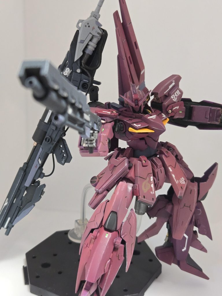 武装はビームライフル、フィンファンネル、背面にバスターライフル、大型ビームサーベル、小型シールドに３連ミサイル、額にメガ粒子砲を装備。火力重視の機体である。