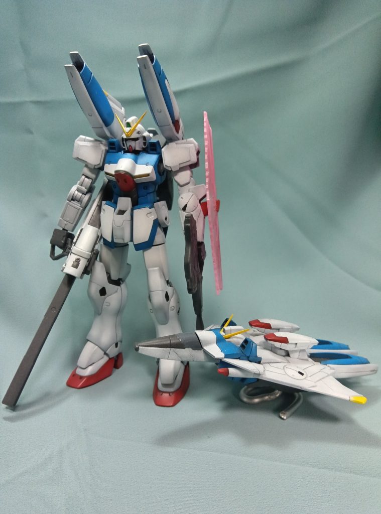 合わせ目が結構多かったり、オールガンダムプロジェクトの共通関節フォーマットのせいで関節が似ても似つかないどころか、本来白いはずの腕関節までグレーだったり、色々と難点も多いキットですが、本体部分の色分けは中々優秀ですし、サイズ感も小型MSらしい小柄な感じが良く出ていますし、付属物も多くて満足度も高いと感じました。しいて言えば、やっぱり腕関節だけは.専用のパーツに変えて欲しかったですが、元のMSと比べた再現度は別として、キット単品だけを見て、この腕関節が格好悪いかと言えば、個人的にはそうでもないと思います。ちなみに、コアブースターの塗り分けに関して、今回は思い付きでやってみて、思ったより上手くいった点があります。これも、すでにどこかで色んな人がやってる手法だとは思うのですが、自分が読んだ本や観た動画などでは紹介されていなかった手法なので、一応紹介していきます。このキットで言えば、コアブースターのオーバーハングキャノンの青い部分と白い部分の塗り分け何かが分かりやすいので、そこで例えます。やり方としては、マスキングテープを青く塗る部分と白く塗る部分、両方を跨いで覆う形ではりつけ、青く塗る部分と白く塗る部分の境界を爪などで良くこすってしっかり馴染ませます。その後、色分けするラインに合わせて、先端が非常に鋭利でしっかりとブレないケガキ用のニードルを使い、ケガキと同じ要領で軽い力で何度もなぞってマスキングテープを切断し、塗りたい部分の方のマスキングテープを剥がして塗装します。自分の場合、ケガキ用のニードルはハセガワのモデリング スクライバー使用しました。デザインナイフと比べて非常に小回りが利きやすいので、刃が滑ったり、変な場所まで刃を当てて余計な傷をつける事が格段に少なく、曲線でも何でも、モールドなどのちょとした段差さえあれば綺麗になぞれるので、曲線や複雑なラインのマスキングはかなりやり易いです。やる前は、もっと切り口が毛羽だって線がガタガタになってしまうかもと思ったのですが、丁寧にやれば思った以上に綺麗な塗り分けが出来ました。欠点としては、あまりに細かく凸凹した部分はテープが馴染まず隙間ができてテープが浮き上がって綺麗に塗り分け出来ないであろうことですが、針でも切れやすい良い感じのマスキングゾルみたいな物が見つかれば応用できるかもです。久々にVガンダムを数十年ぶりに全話観なおして、「やっぱ面白いな」と思ったのを原動力に、だいぶ前に買っていたこのキットを積みプラの山から何とか探し当てて作りましたが、今だと中々買えないキットになっているようなのは残念な所です。「ウッソ＝トリッキーでやたら強い」みたいな印象があったのですが、久々に全話観返してみると、ウッソが本当に無双し始めるのってV2に乗り換えてからで、Vガンダムに乗っていたころは割と苦戦しているのが意外でした。Vダッシュになってからも、子供の頃は妙に好きだったオーバーハングキャノンがあまり活躍しないし、むしろ、専用装備でもない倉庫で拾った旧式のビームスマートガンのほうがよっぽど活躍しますし、子供の頃の自分は本当に描写を全然観ていなかった事を実感しました。冨野監督は一時期は「Vガンダムは酷い駄作」と言っていましたが、それはスポンサーと揉めたり色々で精神的に追い詰められていた事が主な原因であり、後年に改めて振り返ってみると、「Vガンダムも思ったほど悪くなかった」という評価になったようです。実際、戦争の非情な空気感を感じさせる悲惨な展開が多いですが、対して、意外なほど牧歌的な空気感のあるシーンも多く、その「戦場で油断はならないけど、人間は常に張りつめている訳にはいかない」というメリハリが戦記物としてのリアリティになっていると感じました。また、妙な思想を持った癖の強いキャラも多いですが、それが、意味不明な事をわめき散らして「こんなヤバい奴なんです」という薄っぺらい形だけのアピールではなく、細かく丁寧に描写される事で内面が見えてくる感じで上手く表現されていますし、そういう意味では本当にキャラが良いんですよね。登場するMSやその他の兵器も個性的で、タイヤ付きのMS何て、作中の描写を観ると「そりゃ強いわ、考えた人は天才だな。」と思わされたりで、全体的に戦闘シーンの描写も単に作画が良いとかではなく、発想自体が本当に凄いですし、個人的にはVガンダムは名作だと思ってます。キットの話に戻しますが、HGUCのVダッシュガンダムは今だと手に入りにくいみたいですが、素のVガンダムのHGUC版なら割と買いやすい見たいですので、気になったら買ってみるのも良いかもです。合わせ目に関しても、どちらかというとVダッシュになってから追加されたパーツが特に面倒と感じましたし、素のVガンダムの方が気軽に作れると思います。