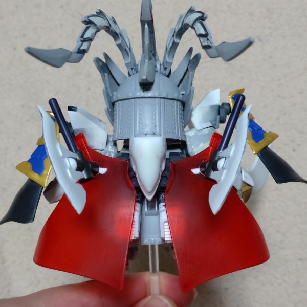 はじめまして、ノンマルトのシ者と申します。プラモデルの改造は初めてですが、色んな方の改造例を参考にひとまずここまで形にしました。三国伝の魏延マークIIがパワーアップした姿をマスクコマンダーをイメージして制作。基本的にはLGBB武者飛駆鳥と黄忠ガンダムを使用。その他装備にはエクスヴァルキランダーや玄武装呂布トールギス、直江兼続頑駄無、三国創傑伝キット等のパーツを流用。流用出来ない部分はプラ板やランナー、パテで自作し、市販のジョイントや関節パーツで形にしています。仮面は黄忠ガンダムの眼帯を改造し取り外し可能です。各種武器は合体させて巨大な武器にも。バックパックは鎧や武器と合体して、マスクコマンダーのICBMハンブラビをイメージした鳥っぽい支援メカに。まだモールドを入れたり修正もして…色も決めなきゃ…^^;（3枚目）