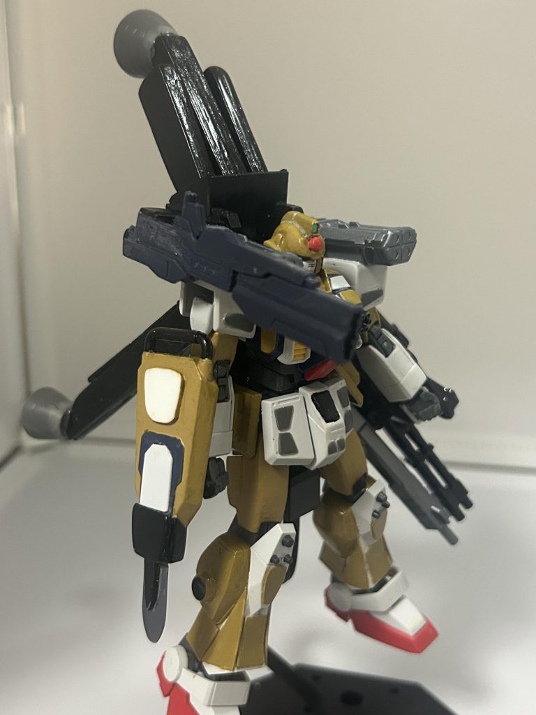 名前はガンダムVanguard ですHG陸戦型ガンダムをベースに装甲(プラ板)と武装を強化した機体という設定。まだそこら辺はあやふやな部分あるけど。右手には盾と実体剣が合体した武装「Vソード(Vanguardの頭文字から)」左手には使い捨てのビールライフルと大型ガトリングを融合した「60mmガトリング砲 STORM」後ろのスラスター部分の名前は「ブラックテイル(黒い尾になぞらえた)」としています(仮)。スラスターの名前は敵がつけた俗称という設定(にした方が面白そう)。肩は「8連ショルダーミサイル　RAIN」です。あとおまけでビールライフルつけてます(部品はMGストフリから)。