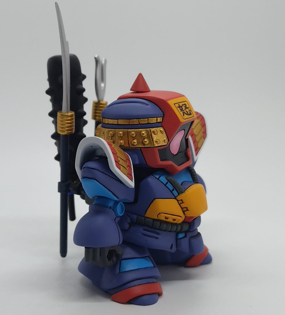 頭部の「怒」はA-one デカールシールで表現。肩鎧はモチーフのドライセン（ドラクン）に戻すことも想定し小型ネオジム磁石でくっつけています。手はモビルスーツ アンサンブルのハンドパーツを３ｍｍポリキャップ接続。頭頂部の角はコトブキヤ プラユニット スパイクで、取り外し可。腕関節の水色丸は同じくプラユニット 丸ノズル (S)。腕バルカンはプラ棒で自作。