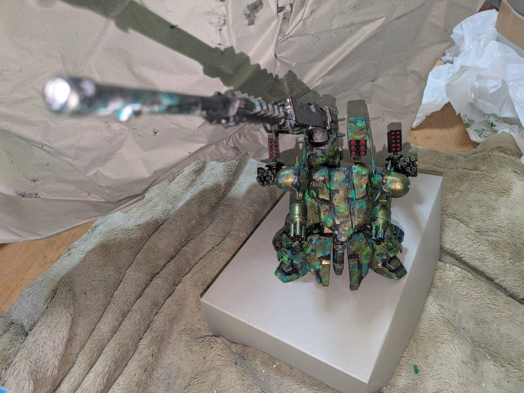 ↑折り畳み式砲（アーマードコアのパーツを）を主砲にしペットボトルのふたを3つ使って砲台に高さをつけて取り付けガトリング砲２門装備してるバックパーツをガンタンクのキャタピラ台をひっくり返してキャタピラ外してプラ板とアルミホイルを使って製作して（アルミホイルはパテ節約の為使用）↓
