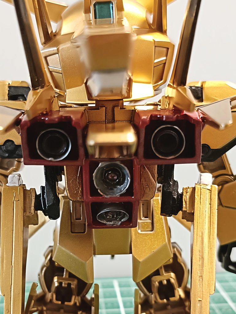 ちょっと写真だと暗くて分かりづらいのですが、バーニアパーツは身近な「金属ハトメ」を買ってきて加工し、ディテールアップに使用しています！​サイド側：ハトメにコトブキヤのバーニアを接着してシャープに。​中央側：ハトメに、細かく切って中心に穴を開けたランナーを接着し、独自の2重構造ノズルを作りました。&nbsp;ハトメの金属地にガンダムマーカーのメッキシルバーを直に塗ってみたのですが、金属との相性が悪かったのか全くメッキにならず、濁ったグレーっぽいシルバーになってしまうというハプニングが発生しました。​外側の側面は落ち着いた「黒鉄色」、内側は「スターブライトシルバー」の上に「クリアレッド」を重ねてギラッと燃えるようなキャンディ塗装に仕上げました。結果として、奥行き感のあるものになったかなと思います。