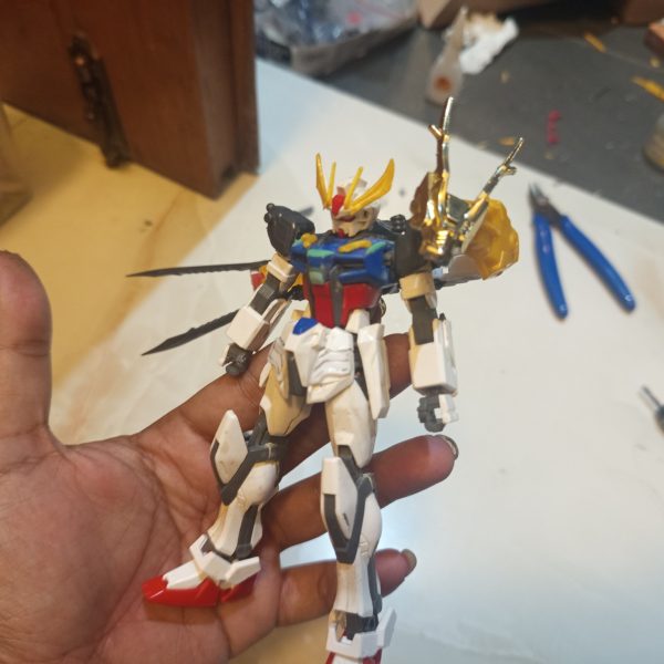 HG 1/144 Strike RyubiThis custom project started from my interest in the SD Ryubi from the SD Brave Battle Warriors line. What attracted me the most was the unique “3 Beast” feature, which works similarly to the striker pack system from the Strike Gundam in Mobile Suit Gundam SEED.However, over time I felt the original SD proportions did not fully match the image I had in mind. The oversized chibi-style head reduced the majestic and warrior-like presence I wanted the design to have. Because of that, I decided to combine it with the body of the Entry Grade 1/144 Strike Gundam to achieve a more balanced proportion.As the project evolved, I continued rebuilding and refining the design. I felt the overall shape still lacked a noble and powerful appearance, and the body’s imaginary lines looked too thin and less imposing. So I decided to do another round of kitbashing using parts from the SD World SDSS Zhang Fei God Gundam from the Sangoku Soketsuden series.I used the waist armor parts to create a more majestic silhouette inspired by traditional Japanese samurai armor. I was also fascinated by Zhang Fei’s claw-like facial ornament, so I adapted those elements into claw details and blade features. The blade parts originally attached to Zhang Fei’s arms were then relocated onto the legs to strengthen the aggressive and heroic feel of the final design.Although this project is still unfinished and continues to evolve, I’m happy because little by little the design is starting to get closer to the image I imagined in my mind. Hehe.(7枚目)