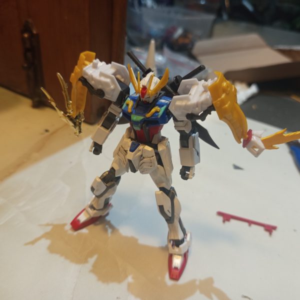 HG 1/144 Strike RyubiThis custom project started from my interest in the SD Ryubi from the SD Brave Battle Warriors line. What attracted me the most was the unique “3 Beast” feature, which works similarly to the striker pack system from the Strike Gundam in Mobile Suit Gundam SEED.However, over time I felt the original SD proportions did not fully match the image I had in mind. The oversized chibi-style head reduced the majestic and warrior-like presence I wanted the design to have. Because of that, I decided to combine it with the body of the Entry Grade 1/144 Strike Gundam to achieve a more balanced proportion.As the project evolved, I continued rebuilding and refining the design. I felt the overall shape still lacked a noble and powerful appearance, and the body’s imaginary lines looked too thin and less imposing. So I decided to do another round of kitbashing using parts from the SD World SDSS Zhang Fei God Gundam from the Sangoku Soketsuden series.I used the waist armor parts to create a more majestic silhouette inspired by traditional Japanese samurai armor. I was also fascinated by Zhang Fei’s claw-like facial ornament, so I adapted those elements into claw details and blade features. The blade parts originally attached to Zhang Fei’s arms were then relocated onto the legs to strengthen the aggressive and heroic feel of the final design.Although this project is still unfinished and continues to evolve, I’m happy because little by little the design is starting to get closer to the image I imagined in my mind. Hehe.(5枚目)