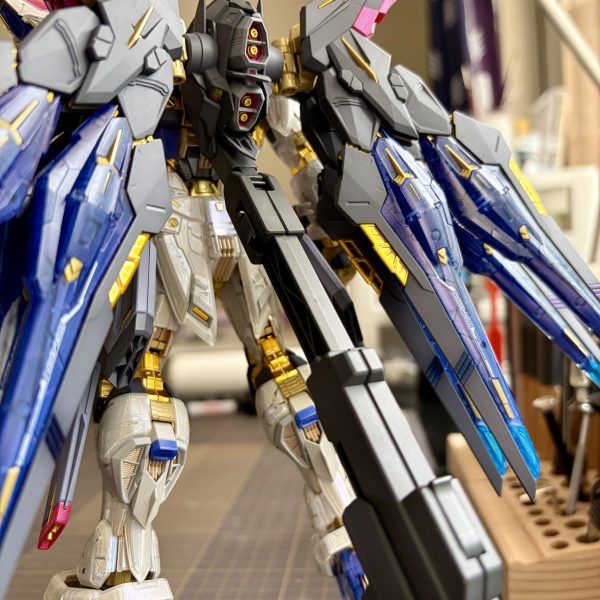 MGEXストライクフリーダム、ほぼ完成しました！部位ごとに塗装を進めたため、同じ調合比でも微妙な色差が出てしまいましたが、それも一つの味かなと思っています。タミヤのX-16の濃度が変わってしまったのも一因かもしれません。でも、全体の仕上がりは予想以上に満足しています。MGEXはディテールが非常に多く、密度感が凄まじいので、今回はあえて外部の墨入れは行わず、デカールも最小限に抑えました（実はデカールの一部は、組み立て時の塗装ハゲを隠すための苦肉の策だったりもしますが(zaku-kao2)。墨入れにはブルーの蛍光塗料を使いました。本当はゴールドの発光が理想でしたが、見つからなかったのでブルーに。でも、これはこれでクールで気に入っています！残るはキラとラクスのフィギュア塗装のみ。これから大阪へ行くので、帰ってきたら最後の仕上げと撮影をしようと思います。PS. 大阪でおすすめの模型店や魂ネイションズのショップはありますか？アメリカの半額近い価格設定を前に、抗える気がしません……。（6枚目）