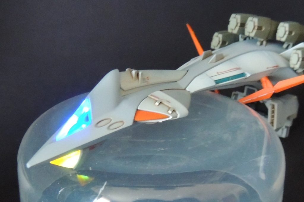 ■機首の電飾について⑴　機首先端のブルーとイエローのクリアパーツを発光させるため、内部に1.2mmLED電飾を3か所仕込みました。使用した商品は、ワンダーウェイのW-PARTS「LEDモジュール磁気スイッチ付リードタイプ3LED［点灯3モード］」であり、3か所を同時に光らせることができます。ブルーのクリアパーツ内部に2個、イエローに1個のLEDを取り付けました。　近年、類似した商品が続々と発売され、LED電飾のキットは家電量販店でも入手可能となってきましたが、今回このモジュールを使用した最大の利点は、「ボタン電池(CR927／3v)ケース兼切り替えスイッチ」のサイズが小さいことにあります。　商品の仕様は、直径約9.0mm、高さ約5.0mm、リード長さ約10㎝、LEDサイズ1.2mmとなっています(※商品の説明書きから引用)。