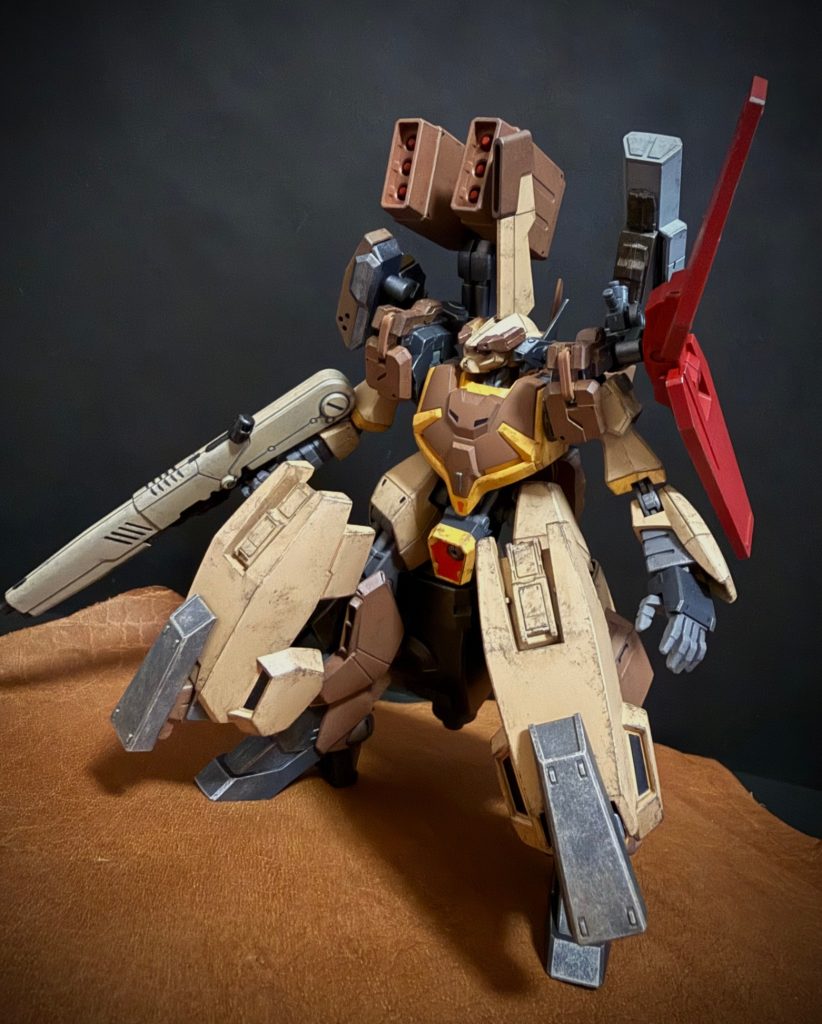 　空中で一旦距離を取るZガンダム。旋回を始めたという事は、撤退する気は無いという事か。僕は素早く機体をチェックする。…武器のチェック、高機能地対空ミサイルが一発。散弾ミサイルが二、右肩の対空バルカンが数クリック分。そして、さっき無茶な機動で体当たりを「かまして」やってから、ずっと鳴り響いている、下半身の、ホバーシステムの異常を知らせる警告音。サブモニタは警告表示で真っ赤だ。…この状態ではZガンダムの攻撃を回避することは出来ないだろう。警告音と共に機体の周りにZガンダムの攻撃による爆発が起きる。僕の機体の状態に気付いたのか、峡谷の向こうの中尉のバーザムや、後方のジムが援護射撃を始める。空中のZガンダムはさっきの散弾ミサイルで主翼の一部を破損したらしい。だが、それでもエゥーゴのフラッグシップMSだ。中尉のビームライフルを左にロールし回避する。「…まただ、…中尉っ！…アイツを峡谷の中に誘き出せませんか、考えがありますっ。…あまりやりたくない方法ですけど」　バズーカ装備のジムと、ほとんど落ちる様に峡谷の底に降りていく中尉のバーザム。見ると、左腕が無くなっている。ゼータプラスとの戦闘で失ったのだ。「…今度は俺が囮だな。…どうすりゃいい」　僕は崖の方へ機体を「走らせ」ながら、「なんでもいい！とにかく峡谷の中へ！…僕が散弾ミサイルで「蓋」をしますっ！」　言って、Zガンダムに向かい対空バルカンを峡谷の方へ注意が向く様に撃つ。同時に峡谷の底に着いた中尉たち攻撃。Zガンダムは僕の方にビームガンを撃ったものの、足元に当たる。そのまま機首を峡谷の底に向けると、僕の前を素通りする様に峡谷へと飛び去る。…目の前を飛んでいったZガンダムは主翼とメインスラスターを破損していた。あれなら機動性能はかなり落ちているはず。急なターンで回避される事は無いだろう。ましては狭い峡谷の中だ。　僕はZガンダムがしっかりと峡谷の中に入ったのを確認し、残った散弾ミサイルを発射。同時に高機能地対空ミサイルをロックオンさせる。峡谷の上空が散弾の花火で「蓋」をされ、Zガンダムは狭い峡谷の中を真っ直ぐ進むしか無い。そして間髪入れず、ロックオンした高機能地対空ミサイルを発射する。発射されたミサイルは、音速を超えるスピードでZガンダムに迫る。しかし、Zガンダムは左にロールすると、背後から迫るミサイルを躱してしまう。…ミサイルはZガンダムを追い抜き、そして、峡谷内の壁面に。「…僕が狙ったのは、『お前』じゃあ無いっ！」　あの、Zガンダムのパイロット。回避の際、機体を左にロールさせてターンすることが多い。あのパイロットの癖なんだ。「飛行機」の旋回はピッチアップ。上昇機動で行われる。つまり機体を傾けた方向に上昇してターンする。可変MSとはいえ、飛行機の形状をしている以上、アイツも同じだ。この狭い峡谷の中で、すぐ壁の側でロールしたら、ターンなんて出来ない！壁面にぶつかり爆発したミサイルは、大小様々な岩を吹き飛ばす。その中に、まるでガラスの破片のような物がZガンダムのうえに降りそそぐ。「…頁岩（けつがん）っ！だぁぁっ！」　この峡谷を構成している岩。頁岩は泥が水中で水平に堆積したものが脱水、固結して出来た岩石。堆積面に沿って薄く層状に割れやすい性質を持つ。メーサや峡谷の壁面が縞模様なのは、この頁岩や、礫岩（砂利などが砂や泥などの基質で固められた堆積岩）、石灰岩（炭酸カルシウムを主成分とする白色もしくは灰色の堆積岩）などが層状になっているからだ。　ガラスの破片の様に、本の頁の様に薄く剥がれ頁岩は、Zガンダムの黒い翼を、白い機体を切り裂くように破壊していく。剥き出しのコクピットの中で僕は、身を乗り出し叫ぶ。「やったぁぁっ……うぉうわぁぁぁっ！？」　僕が、落ちる。Zガンダムの撃ったビームが足元の岩に亀裂を入れていたのか、バーザムの重さに耐えられなかった足元が崩れたのだ。僕と、バーザムは落ちる。数百m下へ、峡谷の底へ。「おーい。生きてるかぁ」　どこかずっととおくで、こえがきこえる。…きがする。…なんかおやくそくのせりふがきこえるようなきがする。　僕は、目を開け…れない！…身体に痛みは…無い…でも、動かない？…熱い？…いや、重い？…どこかで、中尉？の声がする。…ような気がする。…返事をしなくちゃ。口を開くと、中に砂が入ってくる。「うあっ！…うおえっ、ぺっぺっ…ゲホッ、ゲホッ」　咳き込んだ拍子に、頭、というか顔にかかっていた砂や細かい石が落ちたのだろう。僕はやっと目を開けると辺りを見る。…僕は、コクピットの中にいた。ただ、僕の身体は砂に、小さな岩やら小石やらに埋まってはいたけれど。見れば、右腕はそれほど埋まっておらず、顔、口の周りの砂を払うことが出来た。…そうして、口の中の砂やら何やらを吐き出していると、開け晒しのコクピットハッチからバグウェル中尉が顔を出し、「…大丈夫か？って、…ぐっはははははっ！…埋まってんじゃねえか！」　…笑った。…笑うより先に助けるものじゃないんですか？砂に埋まりながら、恨めしそうに睨む僕に、中尉は、すまんすまんと言いながら、砂に埋もれたコクピット内に膝をつくと、砂を掻き出し始める。僕の上半身の辺りの砂を掘りながら、中尉は言う。「…あ〜。変な所触ってしまっても、怒らんでくれよ」　…そんなことどうでもいいですから、…だんだん息苦しくなってきた。…中尉の頑張りのおかげで上半身が自由になり、やっと自由になった両手で下半身の砂を掻く僕に、手を差し伸べ中尉は、「しっかし、ひどい顔だな、お嬢様。その砂や汚れを落とさんとな。…バーケットのやつにシャワーの使用を申請しておいてやる」　さあ。帰るぞ。そう言って差し出した手を握り、砂だらけのコクピットから引きずり出して貰う。僕は半分砂でいっぱいになったコクピットから出ると、砂にまみれた頭をパリパリと掻きながら、落下の衝撃を全て下半身で受け止め、ほぼ上半身だけとなり、砂や岩に埋まったバーザムを見上げる。…ああ、それでコクピットの中に砂が入っていたのか。ジャリジャリの頭を掻き、まだ口の中に残っている砂をモゴモゴと吐き出す僕に、中尉は、「今、上からジムが迎えに来るそうだ。…あと、シャワーの使用許可もとった。…存分に使ってくれってよ」　そう僕を呼び、歩き出す。「もう、下着の中まで砂だらけです」　僕は、中尉の後を追う。