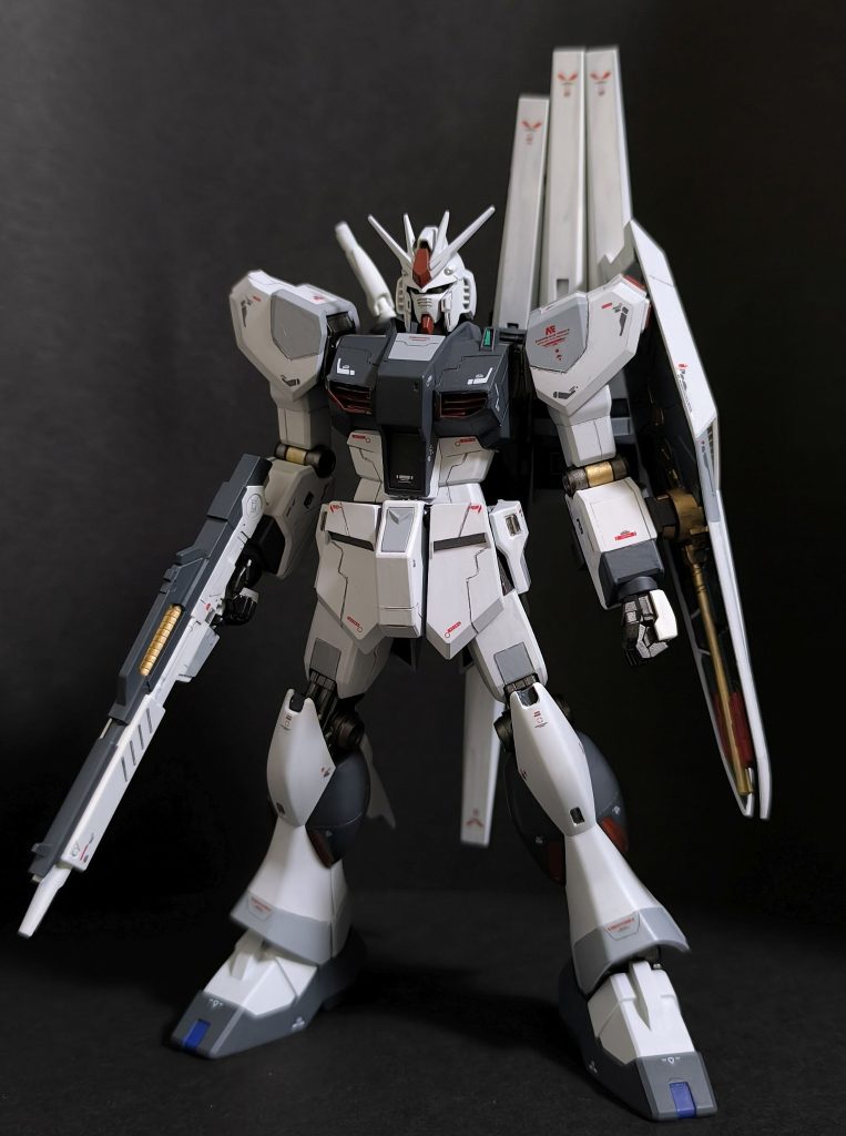 台座から下した、本体素立ちのショット。本機はファーストロットカラーにて仕上げています。νガンダムのオリジナルカラーVer.を制作済なので重複を避けたため、というのが大きな理由です。あとは単純に、ロービジのカラーリングが渋くてそそる、という理由です。塗装はなるべく簡単に済ませたくはあったのですが、成形色のホワイトでは若干ながら青っぽさが足りず、結局全塗装。その他、先人の作例を色々と参考にしながら、各所スジ彫り、膝部の凹み加工など行っています。プロポーションはいじっておりませぬ。設定上、アナハイムエレクトロニクスのテスト機ということなので、デカールは、アムロのイニシャルマークを控えめにしています。（シールドの中央によく見るとAマークありますが…。）