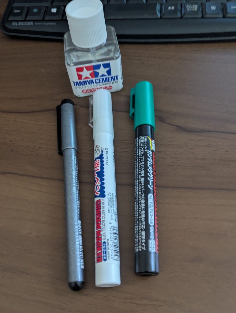 新加入した道具たちパーツの固定に使うタミヤセメントGNドライブの着色用のためだけに購入したメタグリーンガンダムマーカー塗装を失敗した時のための消しペン墨入れ筆ペンが性に合わなかったので、墨入れ用に0.3ミリの細ペン子供時代にもパーツ固定に使っていたタミヤセメントですが、ちょっと今回はやらかしてくれました