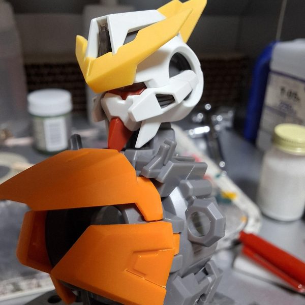 MG キュリオス製作していきます。まずは顔面整形。赤線と矢印のボス切り落として幅詰め。面長のシルエットを目付きの鋭い小顔に強制整形。（6枚目）