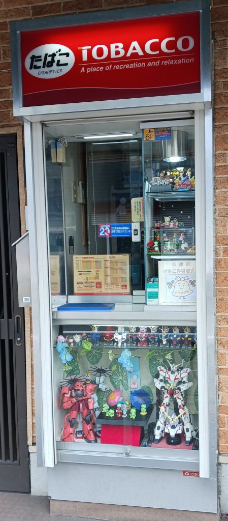 作品名：GUNSTAさん いつもありがとうございます‼️<p>私の家の近所にある『素敵なタバコ屋さん』です😃✨季節ごとに変わる景色が素晴らしいのです。今は梅雨なので傘を持っていますね☂️昨夏、ガンダムが浮き輪を付けていましたし、10月には月見をしていました(正座して)😁私は、タバコ [&hellip;]</p>
