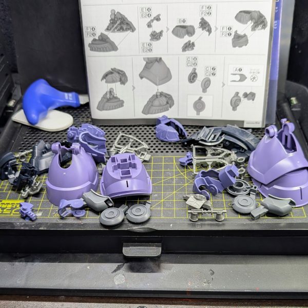​■ 本日の作業：最大の特徴「3本目の脚」の攻略このキットの最大の魅力であり、同時にモデラーの根気を試す最大の試練とも言えるのが、背面フレキシブル・スラスターとして機能する「3本目の脚」です。通常の二脚に加えてもう1本、ヒザから下が全く同じ構造の脚部パーツを、計3つ組み立てる必要があります。​スライド金型が多用された優秀なパーツ構成のおかげで組み立て自体の精度は素晴らしいのですが、やはり同じ作業の3連続はまさに「修行」の感覚に陥ります。今回はひとまず、2本の脚を完成させたところで朝のタイムアップとなりました。​■ こだわりと苦労した点：足裏バーニアとゲート処理画像2枚目の足裏パーツを見ていただくと分かる通り、内部には大小8つのバーニアが密集しており、GQシリーズ特有の高密度なメカディテールがたまりません。​3本脚という圧倒的なパーツボリュームを前に、いかに白化を防ぎつつ、限られた朝の時間で作業を効率化するかが今回の大きな課題でした。​■ 使用ツール：タミヤ 薄刃ニッパーの威力そこで今回大活躍してくれたのが、愛用している「タミヤの薄刃ニッパー」です。切れ味が非常に鋭く、ゲートカット時のパーツへの物理的ストレスを最小限に抑えてくれるため、パープルの装甲でも白化リスクを大幅に軽減できました。切断面が綺麗に仕上がるので、その後のヤスリがけの工程もぐっと短縮されています。同じパーツをひたすら切り出す反復作業において、信頼できる良いツールがいかにモチベーションの維持と疲労軽減に繋がるかを、身をもって実感した朝でした。​残る1本の脚と上位工程は明日の朝活へと回し、これより生徒の試合の審判へ行ってまいります！（3枚目）
