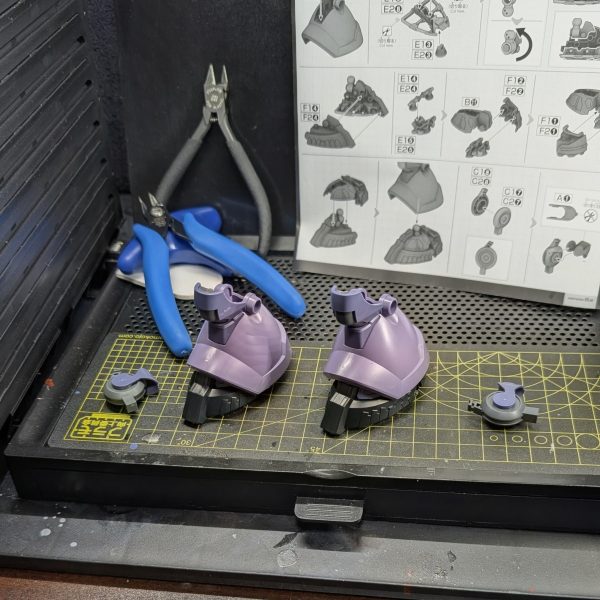 ​■ 本日の作業：最大の特徴「3本目の脚」の攻略このキットの最大の魅力であり、同時にモデラーの根気を試す最大の試練とも言えるのが、背面フレキシブル・スラスターとして機能する「3本目の脚」です。通常の二脚に加えてもう1本、ヒザから下が全く同じ構造の脚部パーツを、計3つ組み立てる必要があります。​スライド金型が多用された優秀なパーツ構成のおかげで組み立て自体の精度は素晴らしいのですが、やはり同じ作業の3連続はまさに「修行」の感覚に陥ります。今回はひとまず、2本の脚を完成させたところで朝のタイムアップとなりました。​■ こだわりと苦労した点：足裏バーニアとゲート処理画像2枚目の足裏パーツを見ていただくと分かる通り、内部には大小8つのバーニアが密集しており、GQシリーズ特有の高密度なメカディテールがたまりません。​3本脚という圧倒的なパーツボリュームを前に、いかに白化を防ぎつつ、限られた朝の時間で作業を効率化するかが今回の大きな課題でした。​■ 使用ツール：タミヤ 薄刃ニッパーの威力そこで今回大活躍してくれたのが、愛用している「タミヤの薄刃ニッパー」です。切れ味が非常に鋭く、ゲートカット時のパーツへの物理的ストレスを最小限に抑えてくれるため、パープルの装甲でも白化リスクを大幅に軽減できました。切断面が綺麗に仕上がるので、その後のヤスリがけの工程もぐっと短縮されています。同じパーツをひたすら切り出す反復作業において、信頼できる良いツールがいかにモチベーションの維持と疲労軽減に繋がるかを、身をもって実感した朝でした。​残る1本の脚と上位工程は明日の朝活へと回し、これより生徒の試合の審判へ行ってまいります！（2枚目）