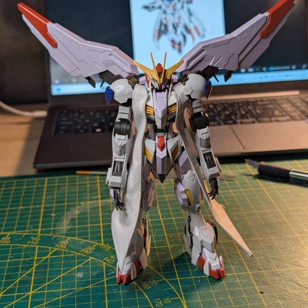 袖なしコート製作のフェーズ1が完了しました！何度も紙で型紙（試作）を作って理想の形を決めてから、布を切り出しています。さらに、ポージングができるようにコートにはワイヤーを仕込みました……！次のステップは、この上にプラ板を追加していく作業です！」（4枚目）