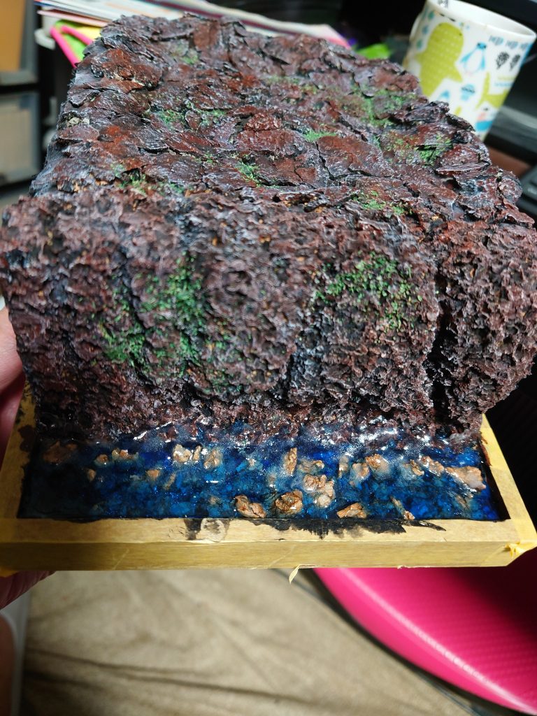 崖はコルクをちぎってそれっぽく。地面は100均のセメントを砕いて着色。こちらでもドライブラシが大活躍。真っ黒に塗った後に白のドライブラシ→茶色のドライブラシ→緑散らし。これはまだ波を付ける前の画像かな？ちぎったコルクを適当に配置して岩っぽく、海は青の100均レジン、さざ波小波で波を表現した後にドライブラシで飛沫を付けてます