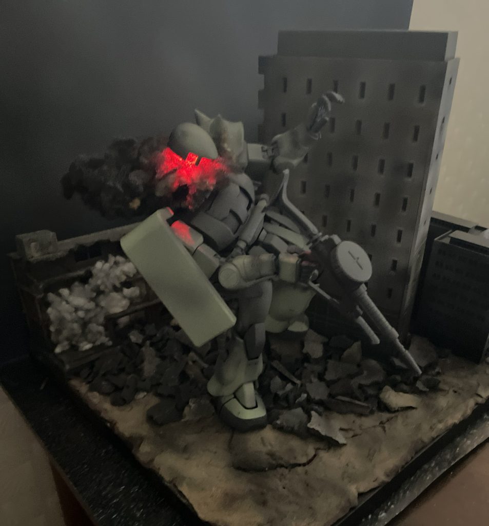 ジオラマ全景です。ビル群はトミーテックのものを強めに汚しを入れて使用しています。MG3体をいれるのでベースのサイズは縦26cm x 縦33cmとやや大型のものを使用しています。背景も箱根技研さんの一番大きなサイズを使用しています。意外にも夜間の背景がなかったので「青空」を購入の上グレーで塗り込んで表現しました。