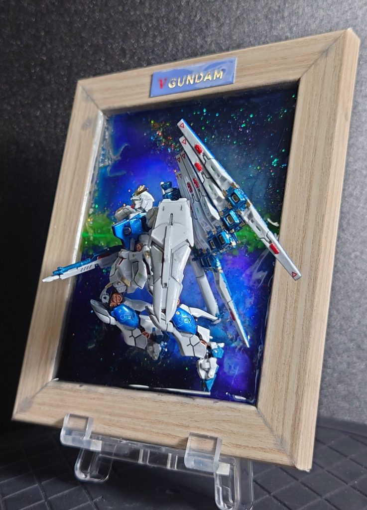 100均フォトフレームにレジンで宇宙を描きフレームから飛び出すイメージにしてます。細かいところでは、フィンファンネルを曲面に配置してみました。なんとなく躍動感が出た様な気がします(gundam-kao5)