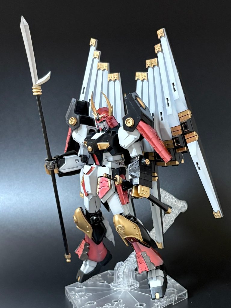 まずは全体像。EGながらとにかくとんでもないボリューム感。3Dモデリングで制作した鎧ですでにズシリと重いところに、ダブルフィンファンネルを装備。まるでMGのような重さです。ダブルフィンファンネルをセットした状態では重量に負け、すぐにヘタりそうな感触があったため、スタンドは必須です。腰パーツにスタンド用の穴が開いていますが、これを使う場合、腰に負担がかかりすぎるため、今回バックパックに新たにジョイント穴用のパーツを仕込んでいます。フィンファンネルの先端にはBB戦士の箱絵を参考に、ゴールドの装飾を施しました。